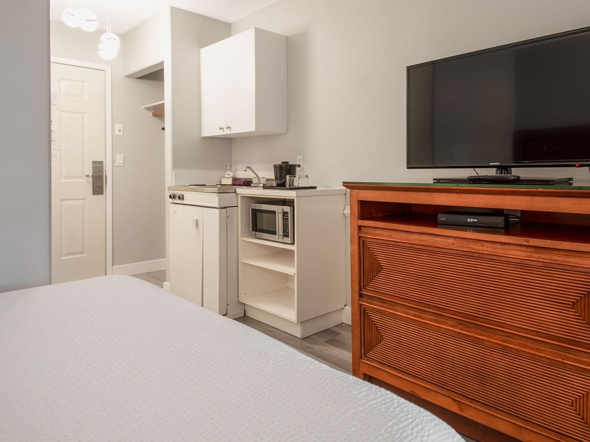 Hotel guestroom with two queen beds, TV, and a kitchenette