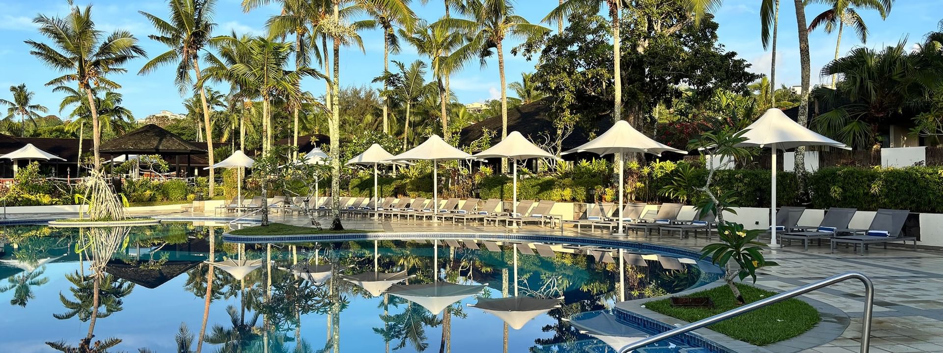 Resort pool and sun loungers under umbrellas in lush tropical garden at Warwick Le Lagon Vanuatu Efate