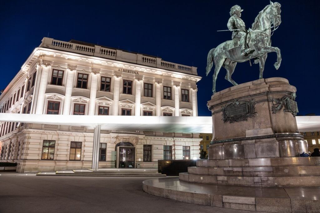 The Albertina Museum in Vienna at night with the equestrian statue of Archduke Albrecht on Albertinaplatz.