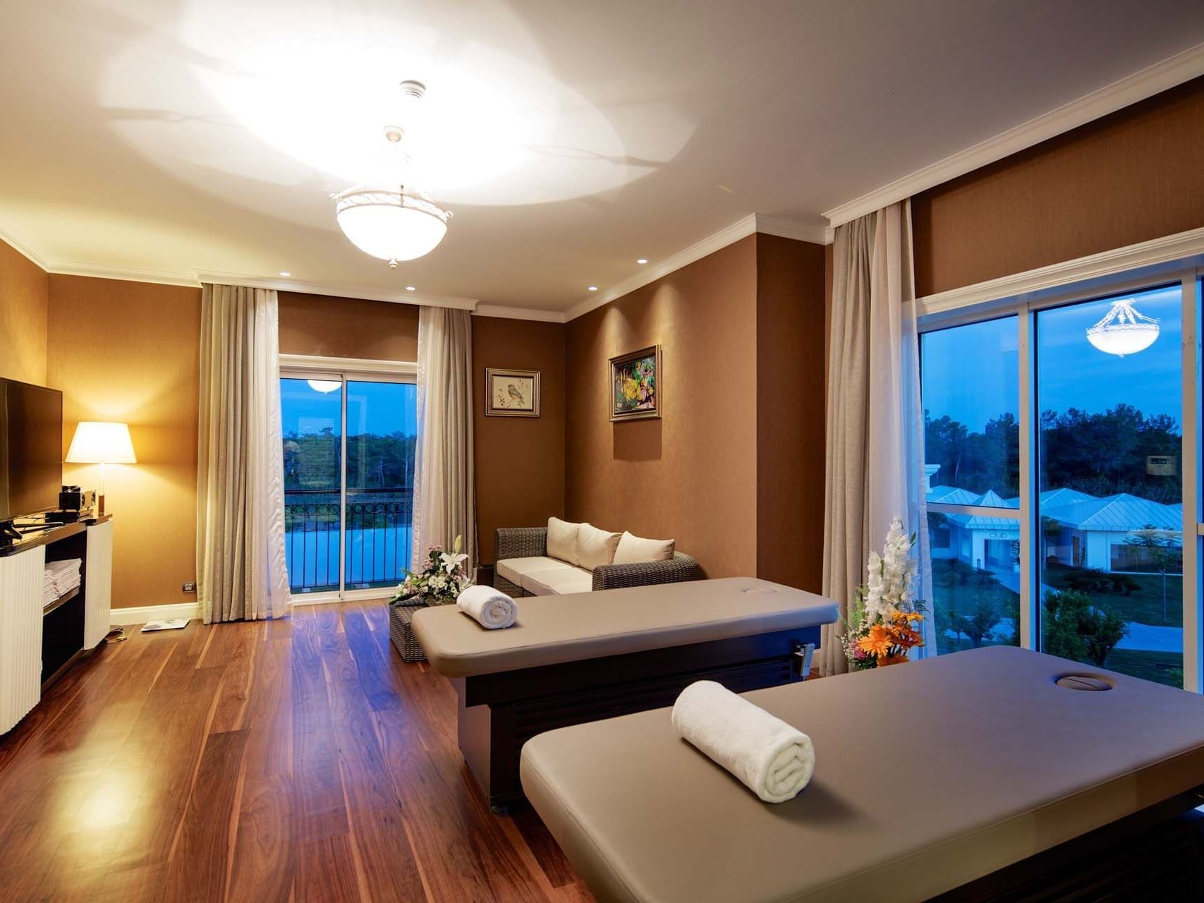 Massage/relaxation area with wooden floors, TV, and comfortable seating in Presidential Villa at Titanic Deluxe Golf Belek.