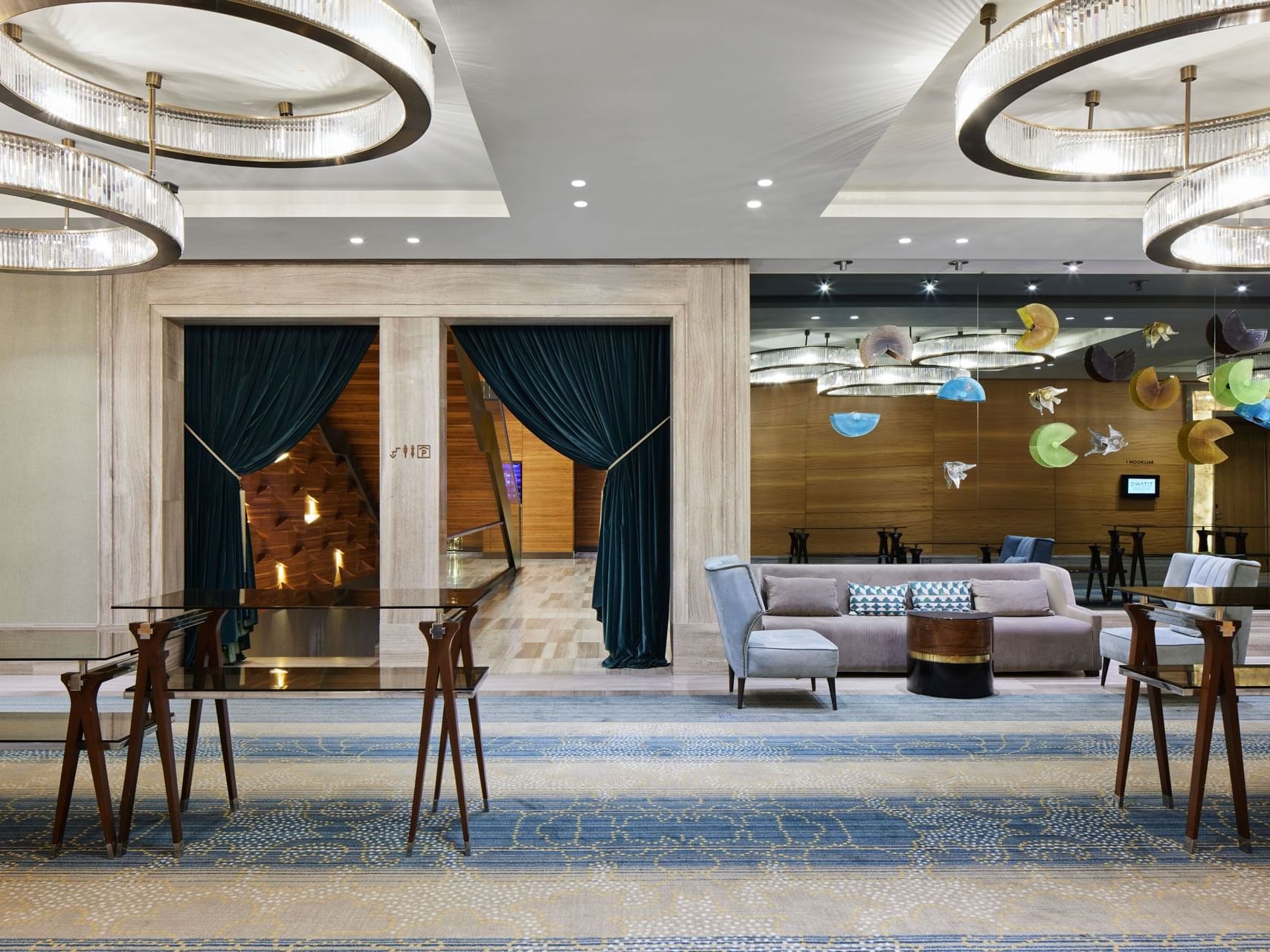 Elegante Lobby mit blauen Teppichen, modernen Möbeln und Kristallkronleuchtern – Titanic Chaussee Berlin.