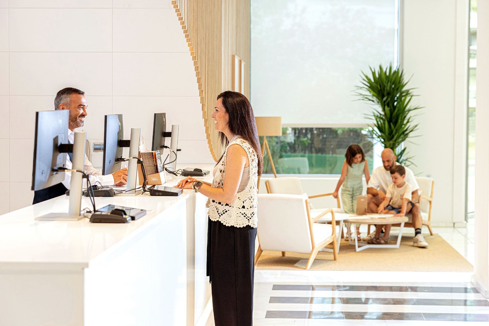 Un huésped conversando con la recepcionista en el mostrador de recepción en Ponient Hotels