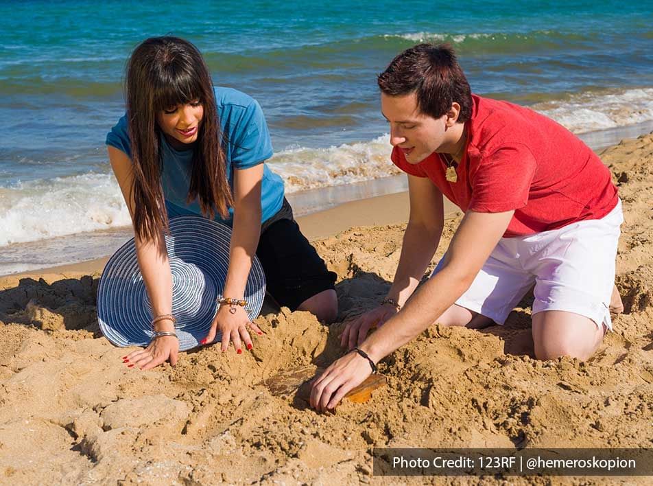 young couple playing with sand on the beach - Grand Lexis PD