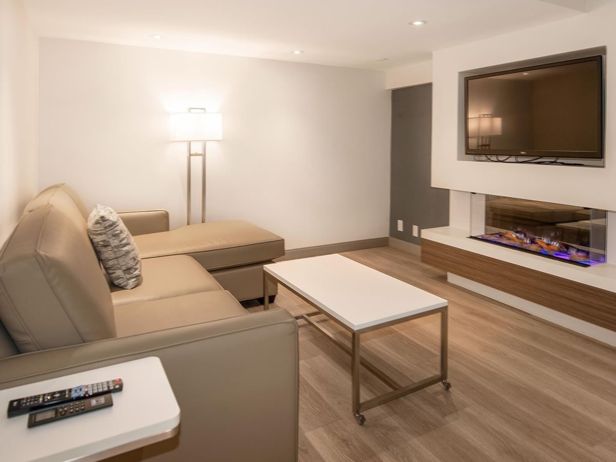 Modern living room with couch, coffee table, TV, and fireplace at Coast Bastion Hotel in Nanaimo.