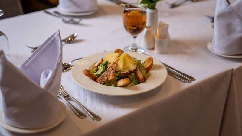 Plate of salad and wine on a table at Saja by Warwick Madinah.