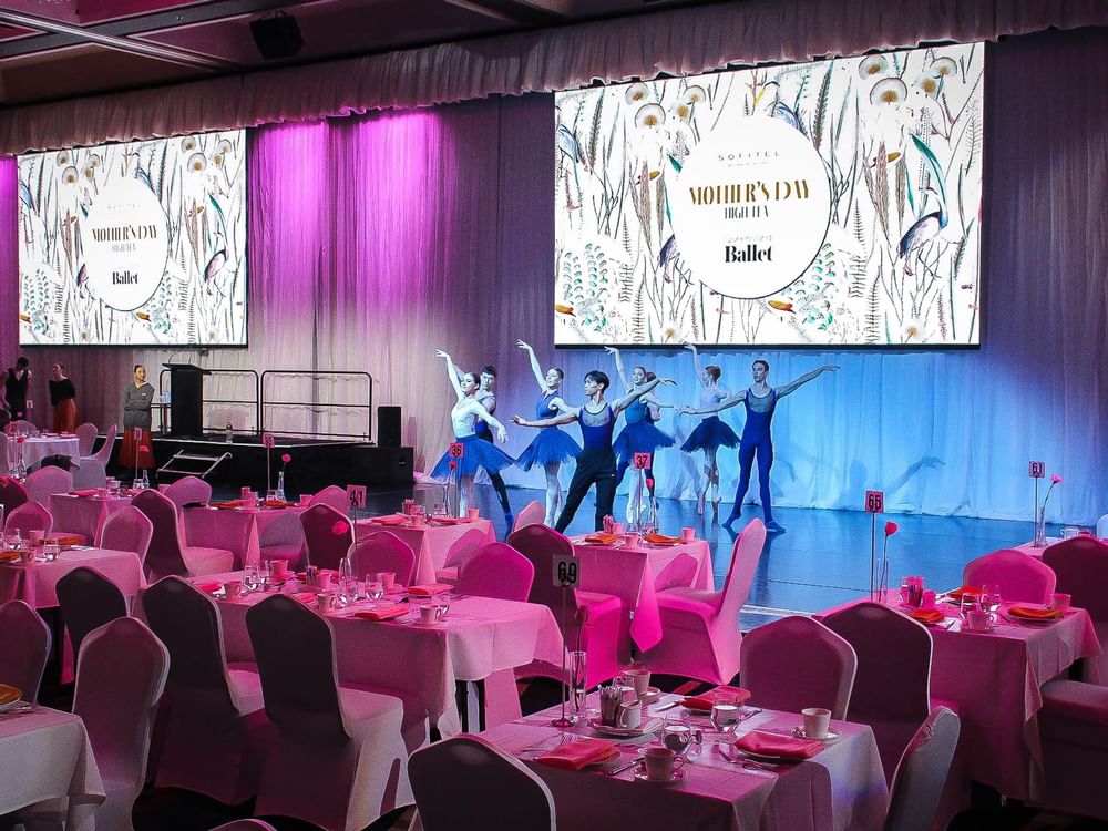 Ballet dancers performing on a stage with pink color-themed lights at Sofitel Brisbane Central