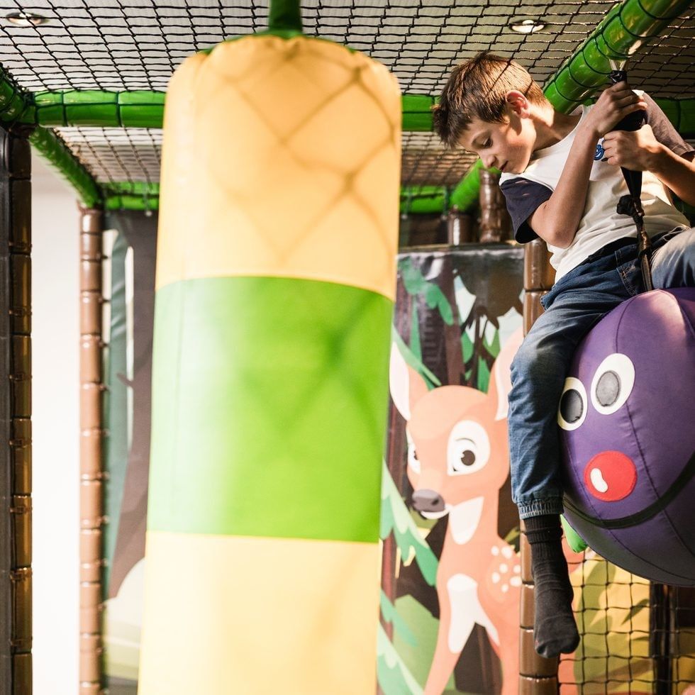 A boy is riding a purple ball in an indoor play area at Falkensteiner Family Resort Sicily