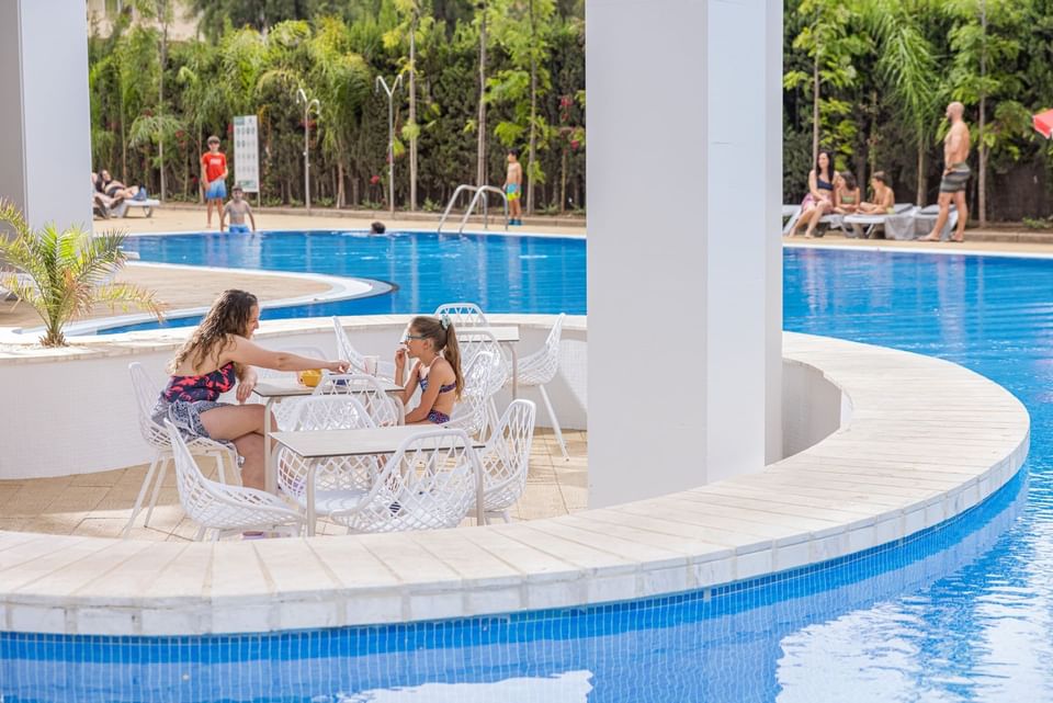 Mother & daughter dining by the outdoor swimming pool at Hotel Piramide Salou