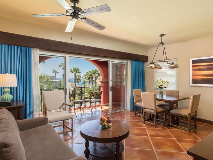 Living area with sofa opening to palm trees and ocean in Luxury Studios 2 Queen Beds at Hacienda Del Mar Los Cabos.