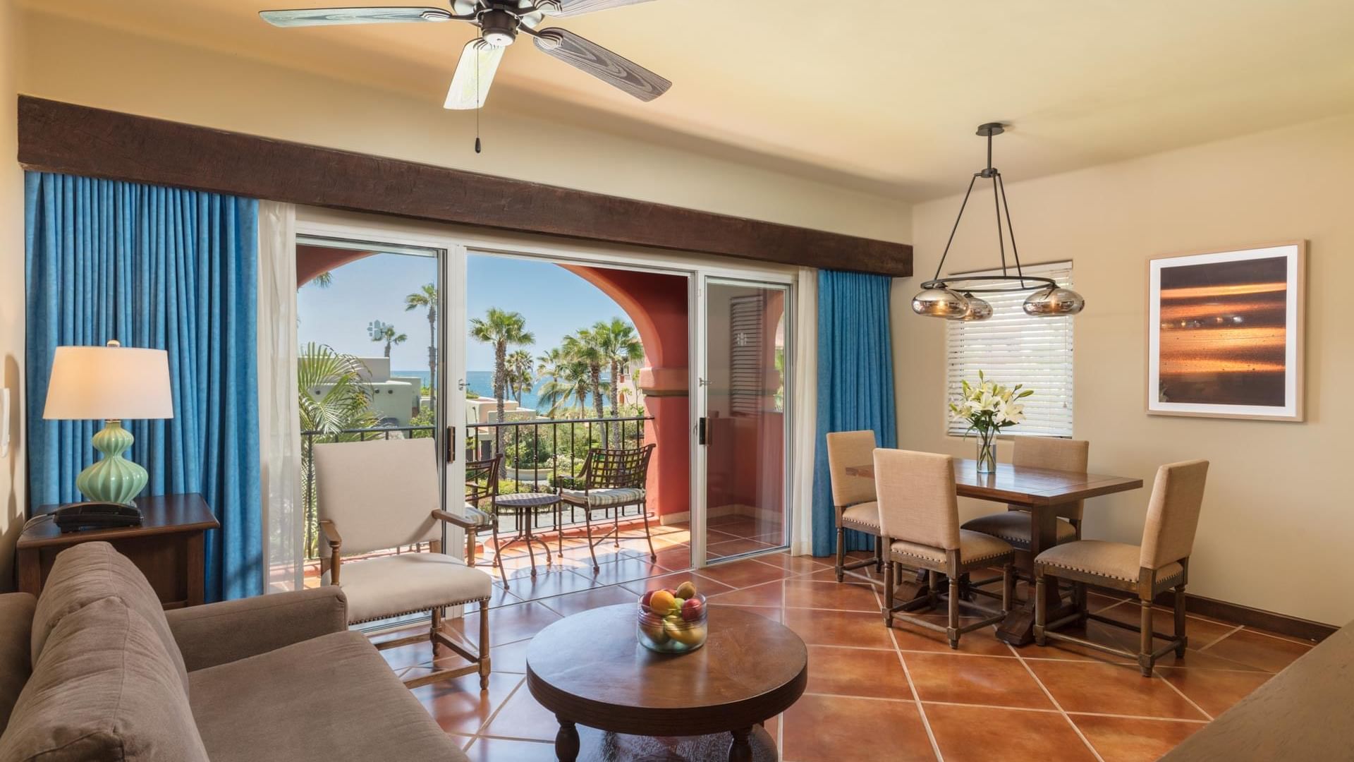 Living area with sofa opening to palm trees and ocean in Luxury Studios 2 Queen Beds at Hacienda Del Mar Los Cabos.
