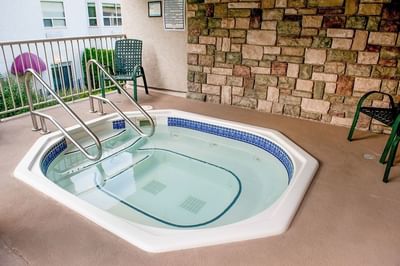 Octagonal hot tub on a patio beside a stone wall with chairs arranged nearby at Hilltop Inn, Salmon Arm