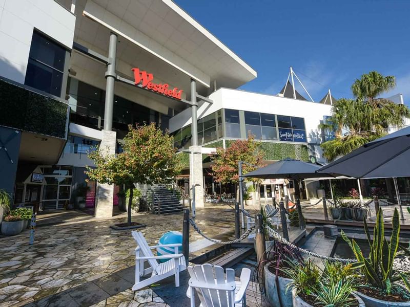Westfield Tuggerah shopping center entrance with outdoor seating and trees near Mercure Kooindah Waters
