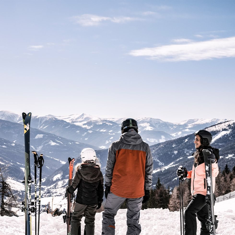 Three skiers looking at snowy mountains near Falkensteiner Club Funimation Katschberg