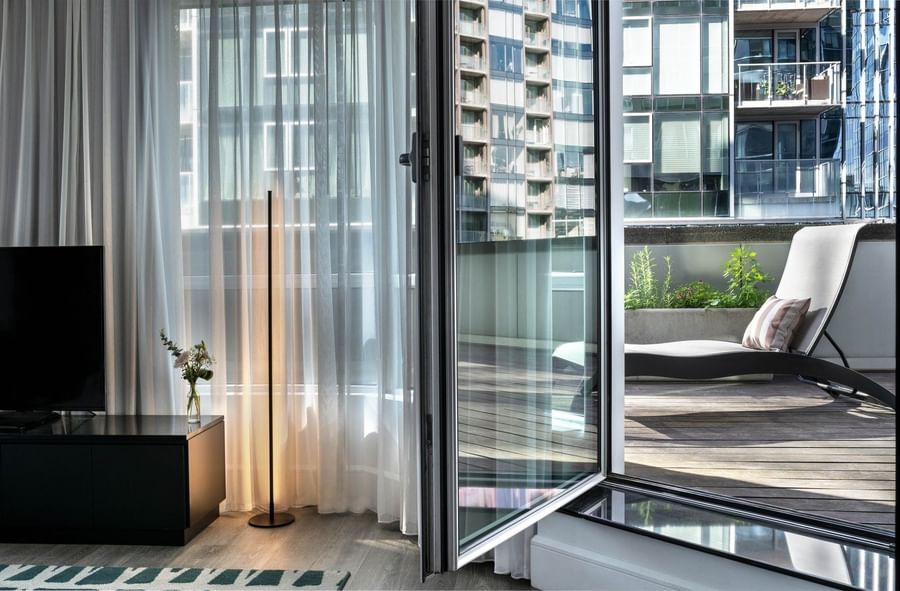 Open balcony door leading to a wooden deck with lounge chairs in Penthouse De la Montagne at Warwick Le Crystal Montreal
