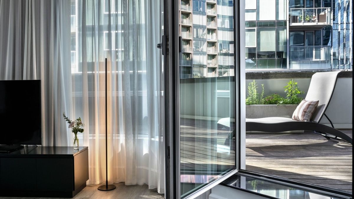 Open door to balcony with lounger and view of building at Warwick Le Crystal – Montreal.