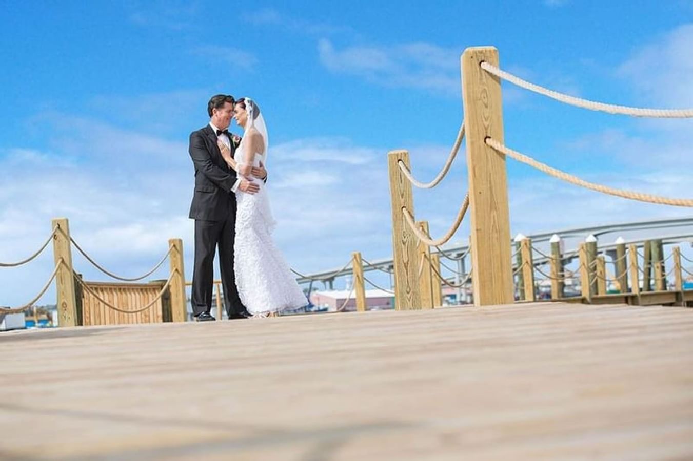 Wedding couple by wooden railings on a sunny deck under a blue sky at Warwick Paradise Island Bahamas