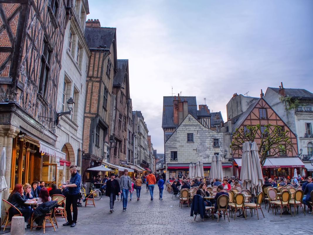 A city street with people enjoying outdoor dining near Oceania Hotels