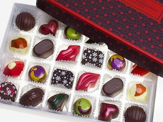 An open box of colorful, artisanal gourmet chocolates featuring various flavors and festive shapes at The Sebel Brisbane