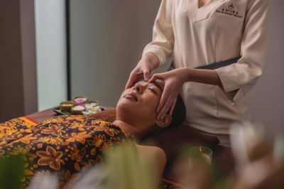 Therapist giving a head massage to a guest in LOM Talay Spa at Amora Beach Resort Phuket