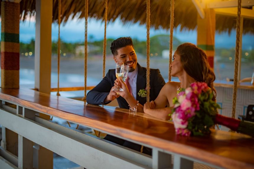 Novios brindando bebidas para sesión de fotos en Fiesta Resort