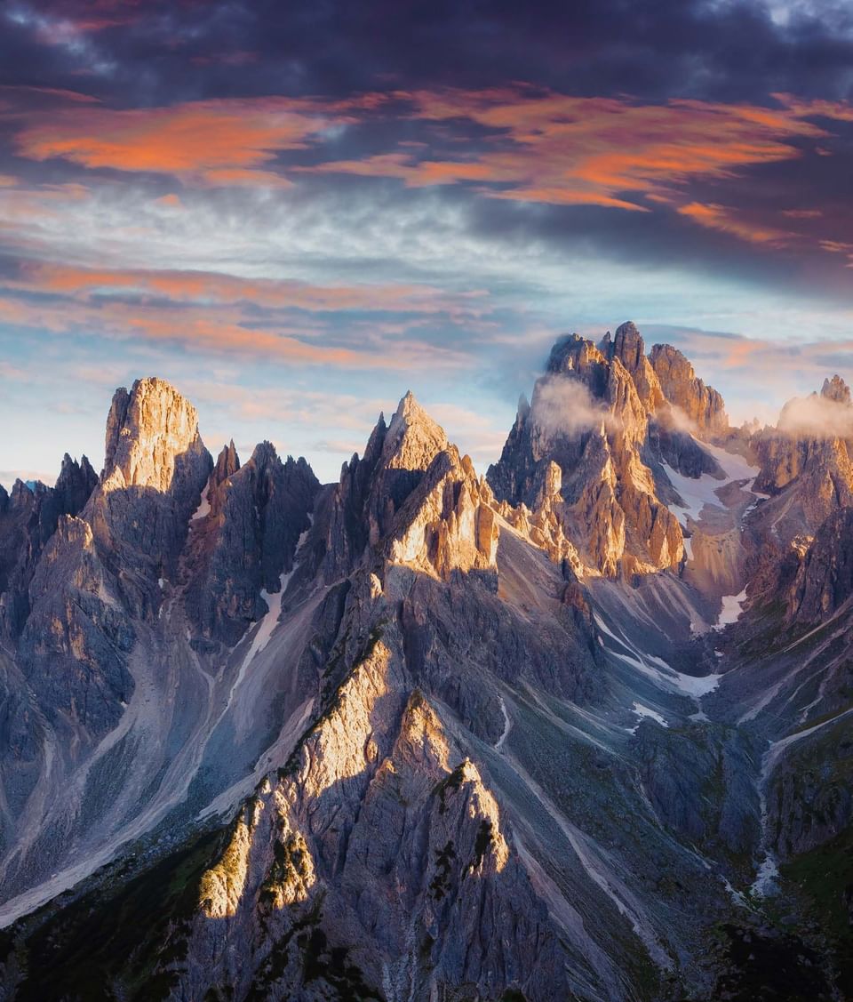 Dramatic sharp mountain peaks of Cadini di Misurina illuminated by warm sunset glow in Dolomites near Meraviglia