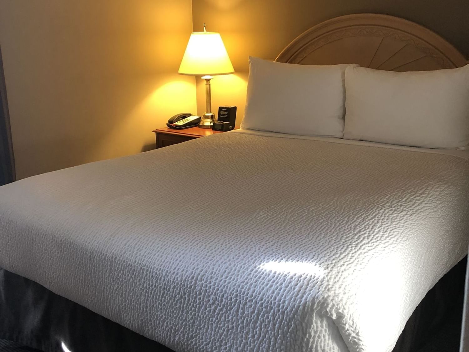Cozy bed with lamp in One Bedroom Suite at Hotels in Fort McMurray