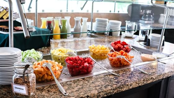Bufé de desayuno con tazones de fruta, granola, jarras de jugo y platos apilados en Fonda De Hermosillo, Araiza Hermosillo 