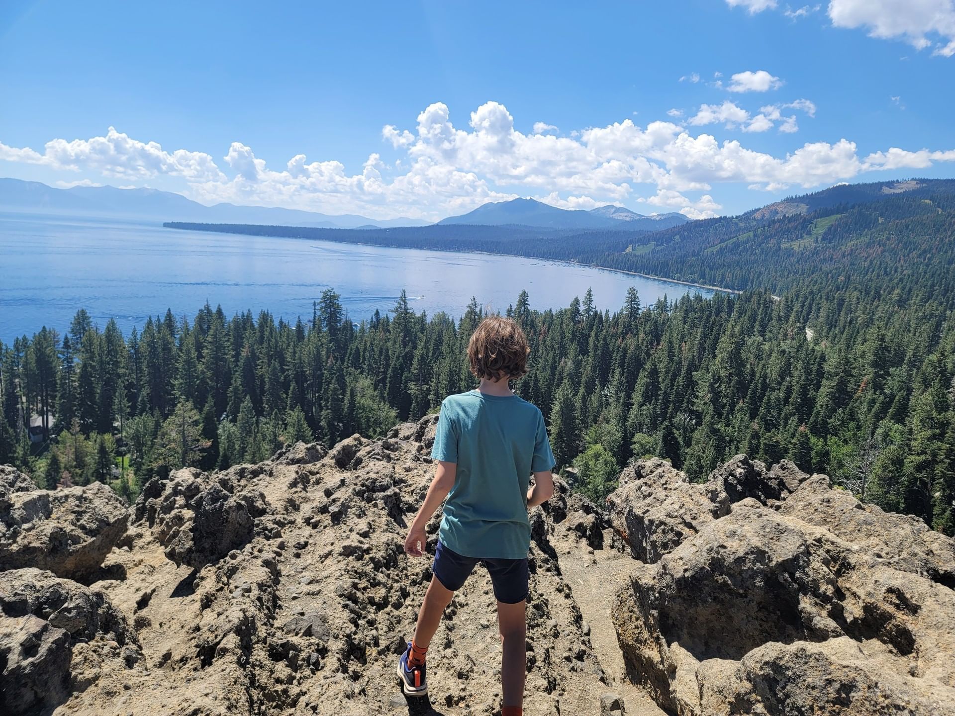Child on top of Eagle Rock in Homewood, CA, overlooking panoramic view of Lake Tahoe