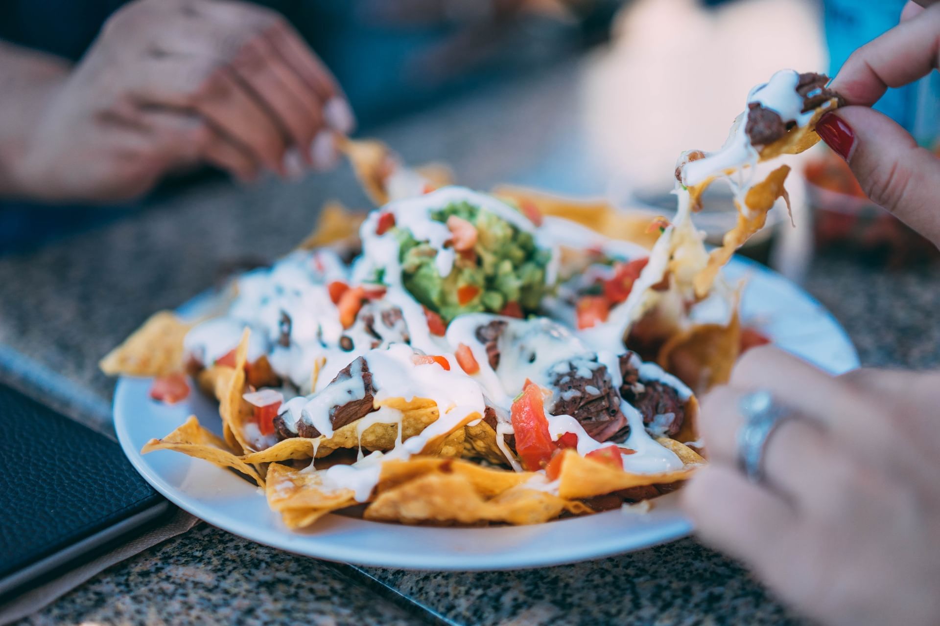 hands grabbing cheesy nachos