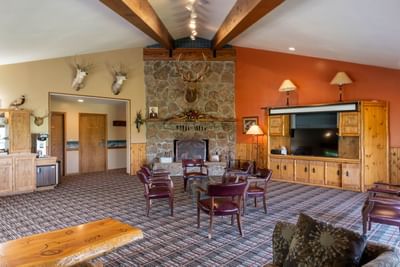 Spacious area at The Ranch at Ucross with a stone fireplace, mounted deer heads, and comfortable seating