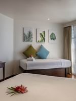 Cozy bed by a wood desk under leaf art with a side table in Ocean View Rooms at Warwick Fiji Resort and Spa