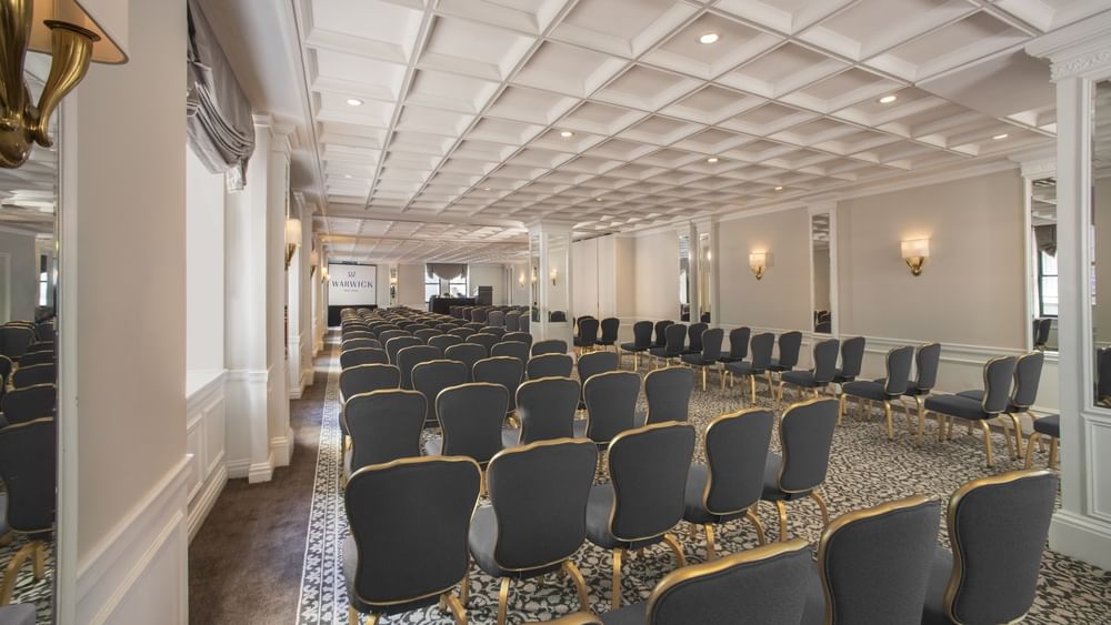Theater set-up facing screen under warm light in Surrey meeting room at Warwick New York