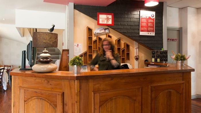 A receptionist at the reception desk in Hotel Le Cheval Rouge