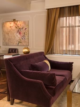 Plush purple sofa & glass coffee table with small dining area in Follie Suite at Warwick New York
