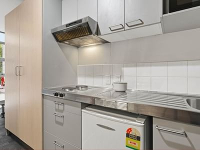 Modern kitchen with stove, sink, fridge, and cabinets at Student Living Auckland - Beach.