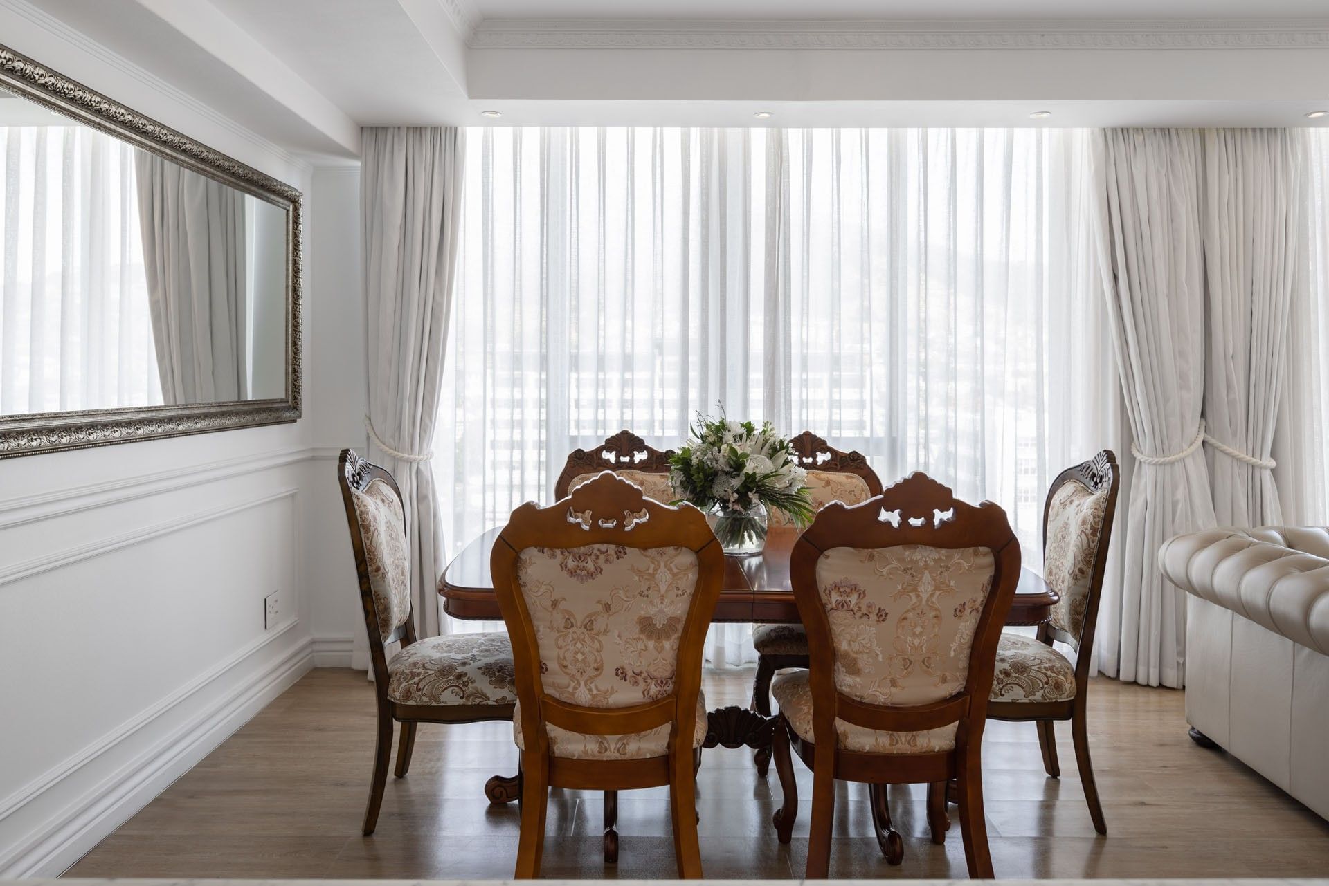 Premier Two Bedroom Suite dining room featuring a wooden table with patterned chairs, mirror, & curtains at Pepperclub Hotel