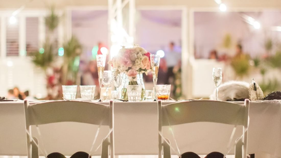 Wedding table with floral centerpiece and chairs, glowing with soft lights in Receptions at Mercure Hotel Townsville