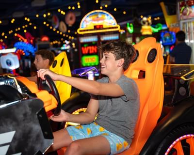 Boys playing arcade racing in Lucky Snake Arcade & Sports Bar near Showboat Hotel & Resort