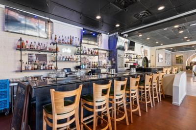Modern bar area at The Gavel, The Riverwalk Plaza Hotel, with liquor shelf, wooden stools, and warm ambient lighting