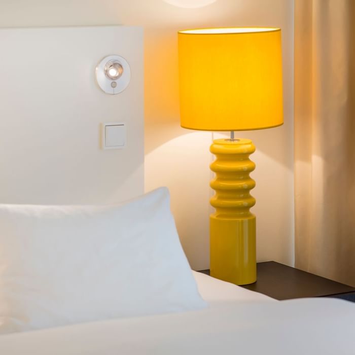 Table lamp beside a bed in a room at Falkensteiner Hotels