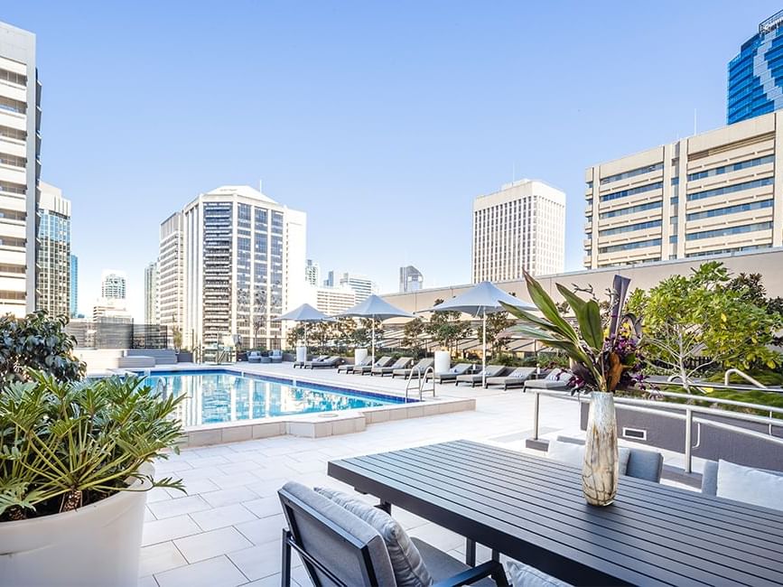 Rooftop pool with city skyline, loungers, and dining area at Sofitel Brisbane Central
