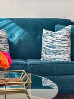 Blue tufted sofa with patterned pillows by a gold coffee table in Presidential Suite at Warwick Melrose Dallas