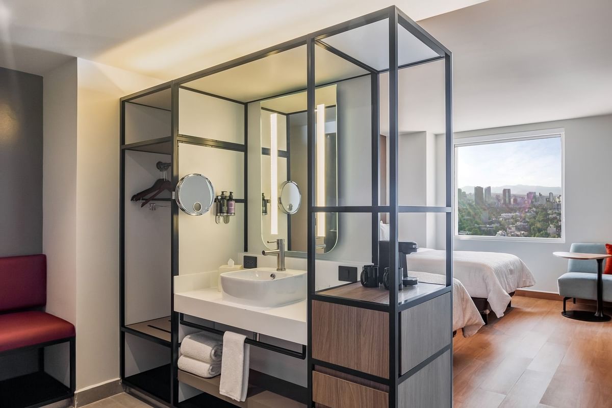 Interior de habitación con lavabo moderno y tocador separando el área de descanso en Fiesta Inn