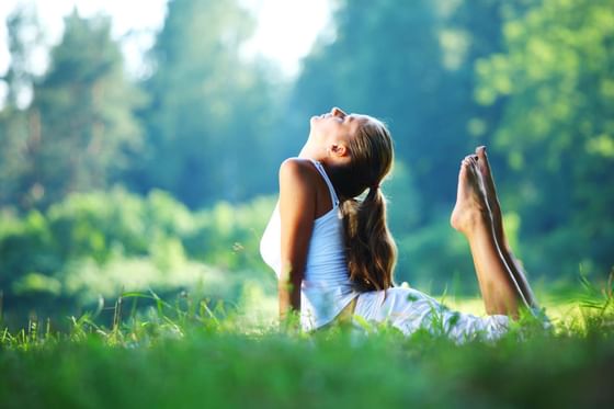 A woman stretching in a park near Honor’s Haven Retreat