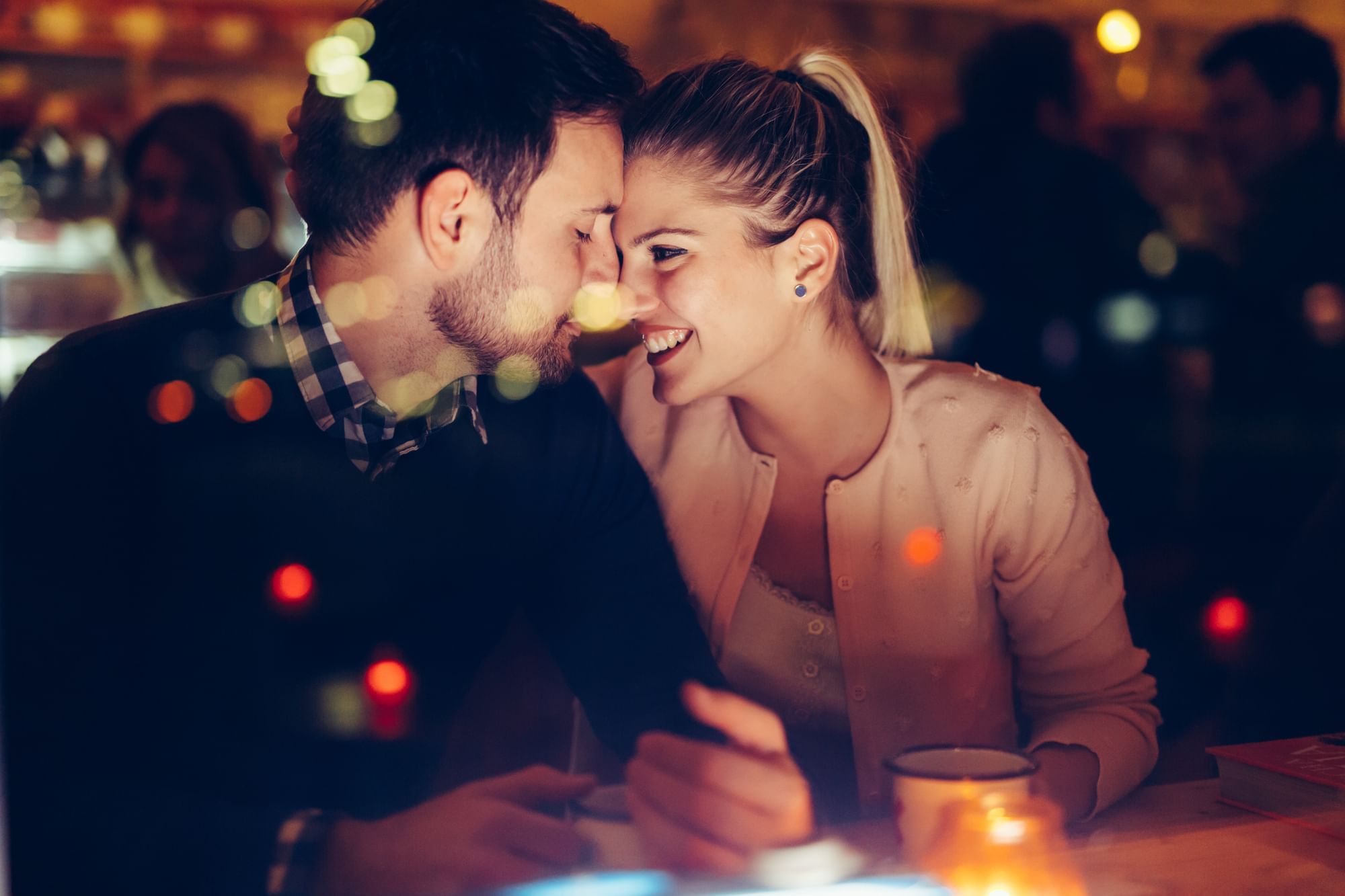 Couple shares an intimate moment with drinks and warmly lit candles on the table at Cove Pocono Resorts