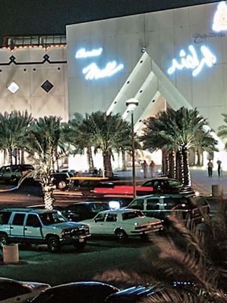 Al Rashid Mall by palm trees under a night sky, surrounding a busy parking area near Naviti by Warwick Al Khobar