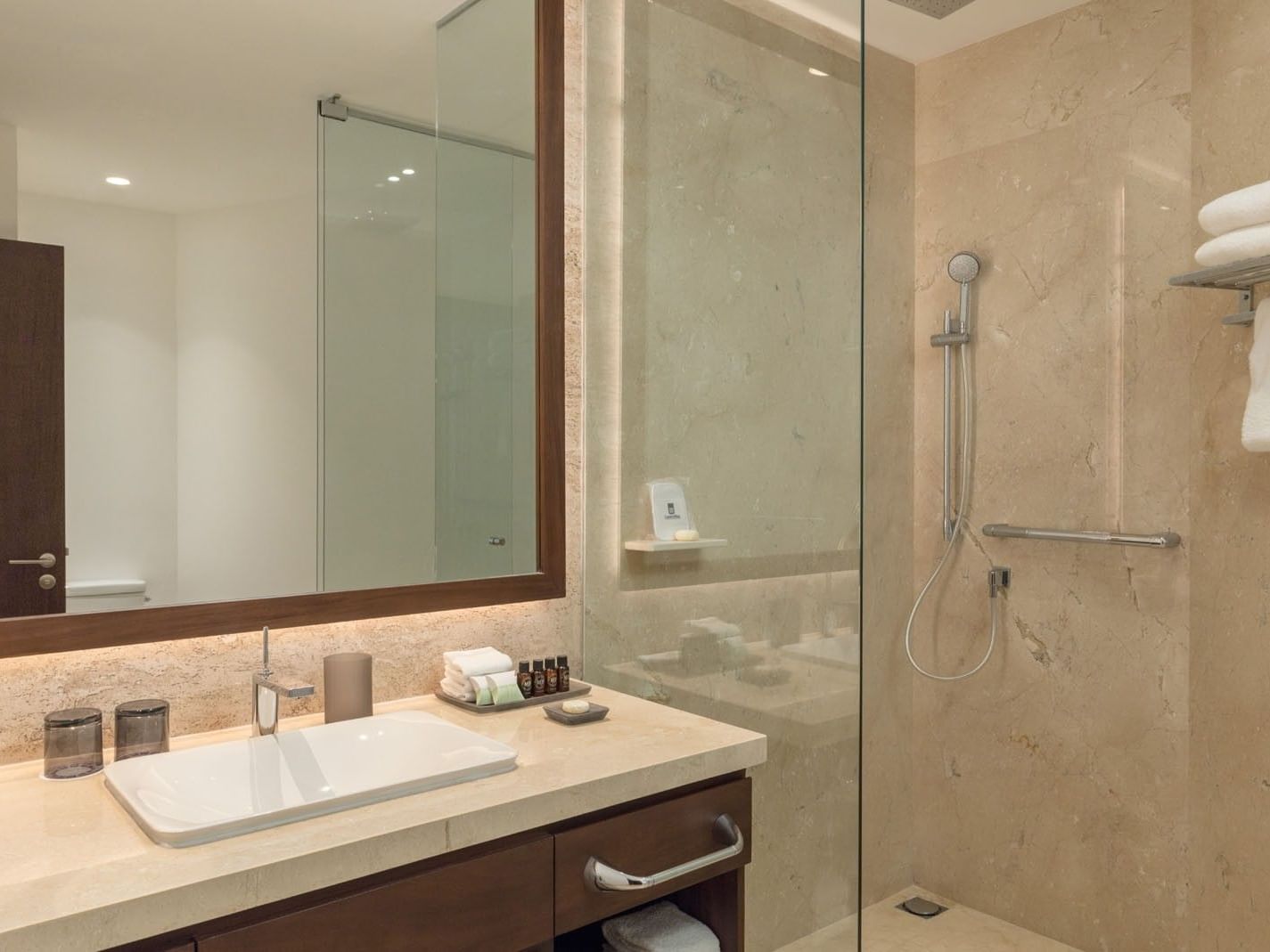 King Camino Real Club walk-in shower with beige marble tiles, sleek fixtures, and a vanity mirror at Camino Real Merida