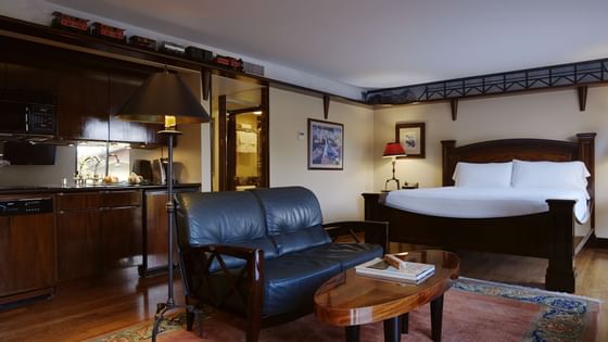 lounge area with bed, black sofa, carpet and wood floors