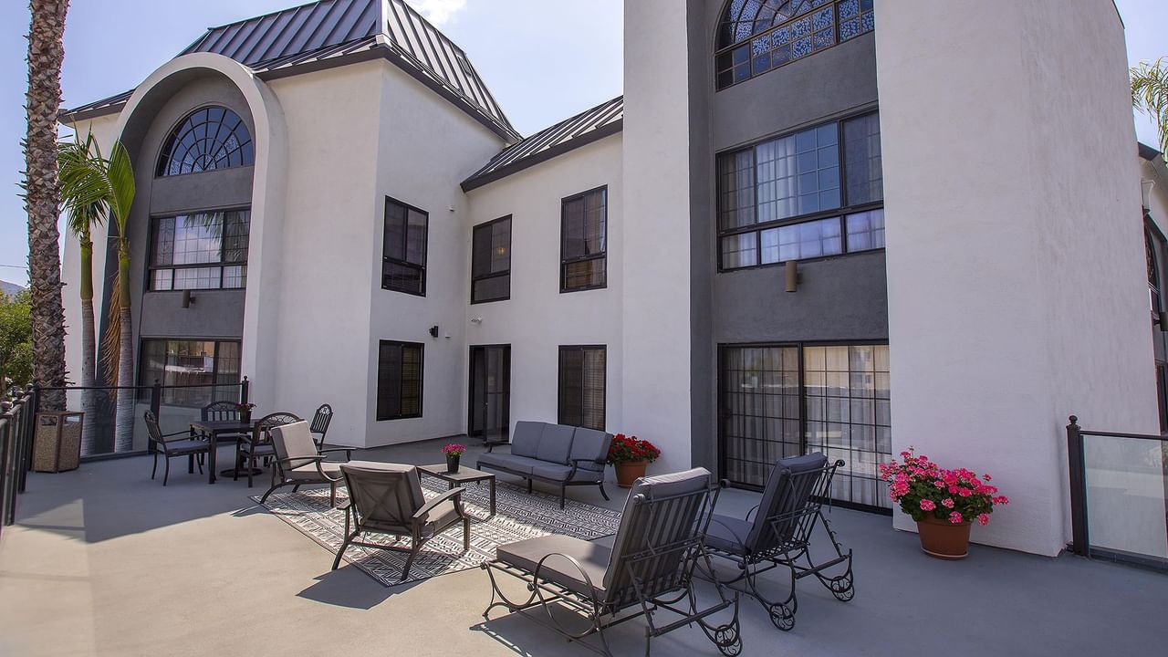 An outdoor sun deck with lounge chairs, tables, and potted plants.