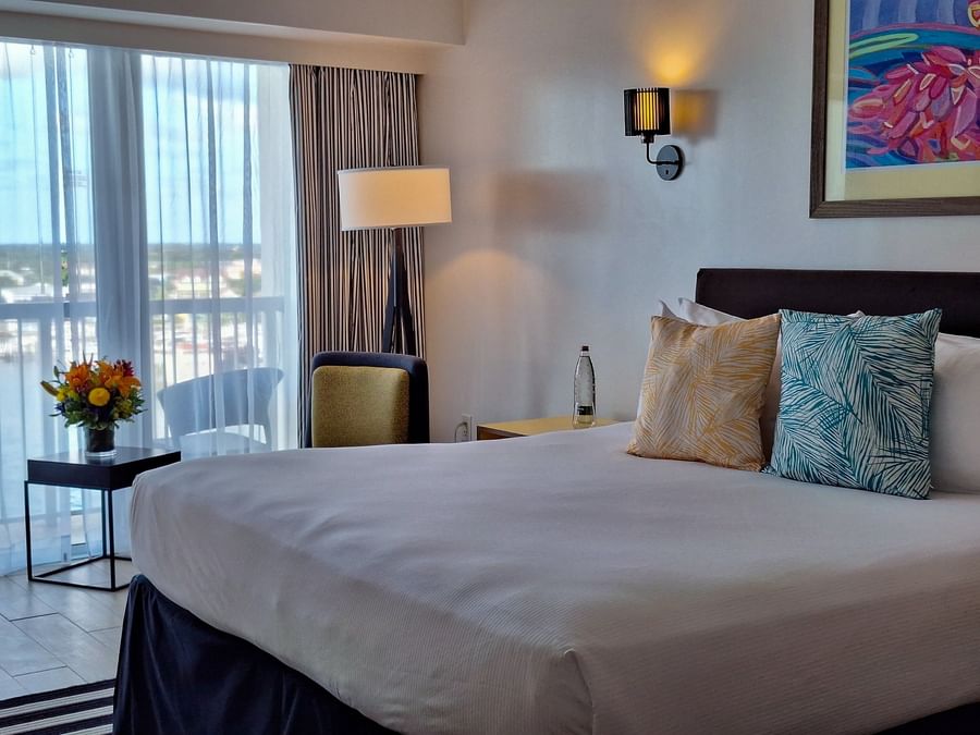 King bed by a balcony with a chair and a small table in Harbour Deluxe Balcony at Warwick Paradise Island Bahamas